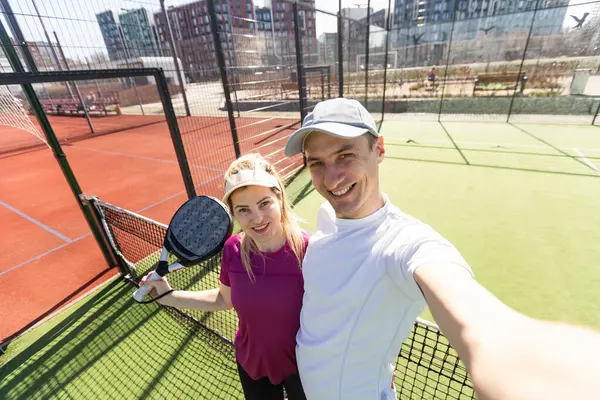 Paddle tennis woman and man team posing in wide angle image. High quality photo