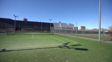 Yüksek pleksiglas ve metal çitleri olan bir tenis kortu olan yerleşim yerinin peyzajlı alanları. Yüksek kalite fotoğraf