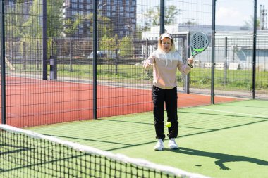Genç, sportif bir kadın, raket tenisi antrenmanı sırasında basit hareketler yapıyor. Yüksek kalite fotoğraf