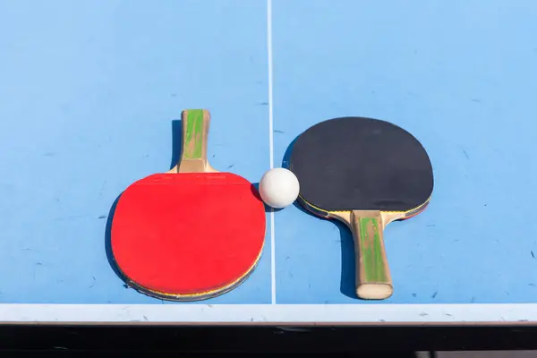 Red and black Table Tennis Paddles and ball on the blue table tennis table with net. Ping Pong concept with copy space. High quality photo