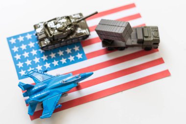 Amerikan bayrağı altında bir savaş uçağı, haki yeşili bir tank ve Amerikan bayrağında duran askeri bir araç. Yüksek kalite fotoğraf