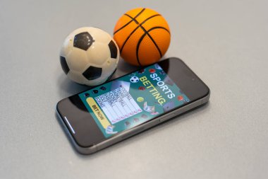 Spor bahisleri uygulamalı akıllı telefon ve basketbol topu, online bahis konsepti.