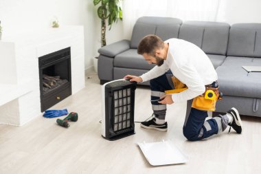 young man changing - fixing a dirty air purifier HEPA filter after using for a long time. A repairman replacing and installing the air purifier filter. Healthcare and wellbeing.