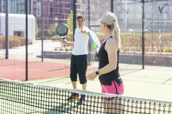  Genç bir kadın açık hava tenis kortunda partneriyle Padel Tenis oynuyor. Yüksek kalite fotoğraf