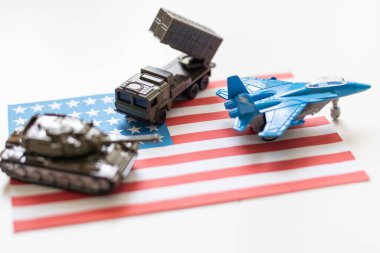 Amerikan bayrağı altında bir savaş uçağı, haki yeşili bir tank ve Amerikan bayrağında duran askeri bir araç. Yüksek kalite fotoğraf