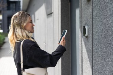 Kadın akıllı telefonla kapıyı açar. Yüksek kalite fotoğraf