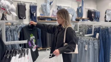  Genç bir kadın giyim mağazasından gömlek seçiyor. Yüksek kalite fotoğraf