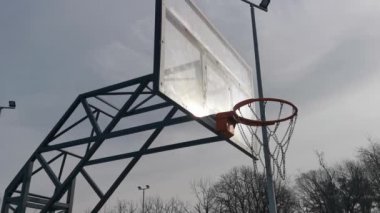 Bulutlu gökyüzünün altında bir basketbol ağı. Arka tahtası kırılmış ve şimdi de büyük bir tahta parçasıyla kaplanmış. Yüksek kalite fotoğraf