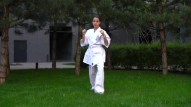 Beyaz kemerli, aktif genç bir kız dövüş sanatları tekmeleri atıyor. Çin köprüsünde dövüş tekniğini geliştiren karateci kadın. Spor anlayışı. Yüksek kalite fotoğraf