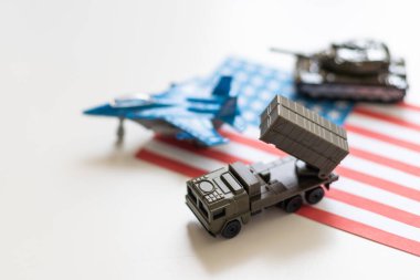 Amerikan bayrağı altında bir savaş uçağı, haki yeşili bir tank ve Amerikan bayrağında duran askeri bir araç. Yüksek kalite fotoğraf