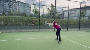 Açık tenis kortunda diğer oyuncularla Padel Tenis oynayan aktif bir kadın. Yüksek kalite 4k görüntü