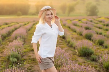 Lavanta tarlasında duran genç bir kadın ve arka planda gün doğumu..