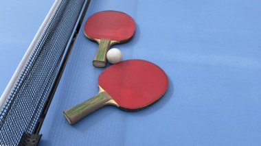 Mavi bir masada ağlı iki masa tenisi raketi ve topları. Yüksek kalite fotoğraf