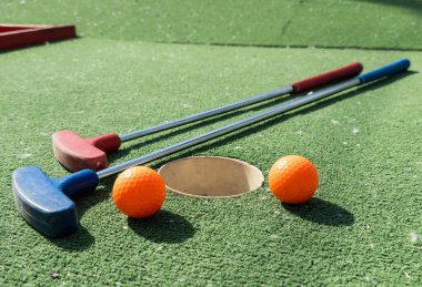 Mini golf sopaları ve farklı renkte toplar suni çimlerin üzerine konmuş. Yüksek kalite fotoğraf