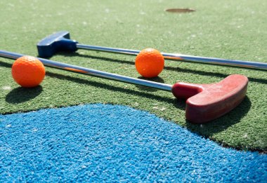 Mini golf sopaları ve farklı renkte toplar suni çimlerin üzerine konmuş. Yüksek kalite fotoğraf