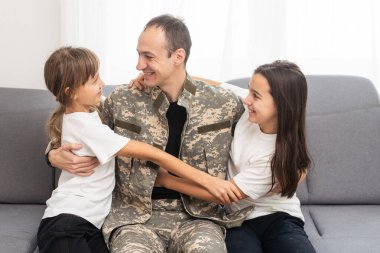 Küçük çocuklar evde askerî babalarına sarılıyorlar. Yüksek kalite fotoğraf