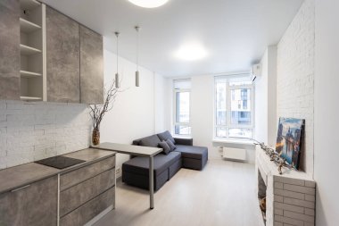 Minimalist kare mobilyalar, gri zemin ve duvarlar, önünde entegre lavabo ve bar tabureleri, dahili mikrodalga fırın ve ocağı olan geniş bir mutfak. Yüksek kalite fotoğraf