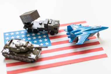 Amerikan bayrağı altında bir savaş uçağı, haki yeşili bir tank ve Amerikan bayrağında duran askeri bir araç. Yüksek kalite fotoğraf