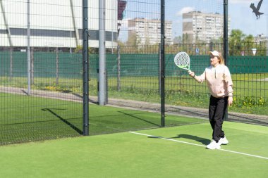 Genç, sportif bir kadın, raket tenisi antrenmanı sırasında basit hareketler yapıyor. Yüksek kalite fotoğraf