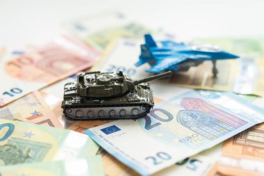 100 dolarlık banknotlardaki oyuncak tankları kapatın. Savaş maliyetleri, askeri harcamalar ve ekonomik kriz kavramı. Yüksek kalite fotoğraf