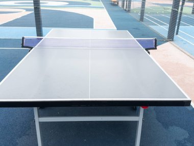 Çimenlik mavi metalik çimlerin etrafındaki parkta tenis masası. Sun Game oyuncuları, hiç kimse, okul bahçesi. Yüksek kalite fotoğraf