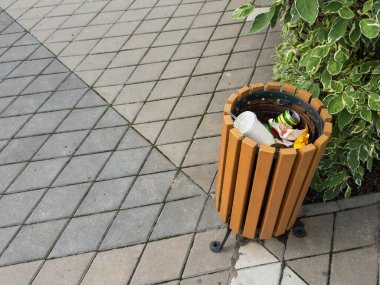 Çöp torbasıyla dolu bir çöp kutusu halka açık bir yere, bir parka yerleştiriliyor. Kaldırıma yakın bir yerde. Yüksek kalite fotoğraf