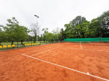 Wet clay tennis court with puddles during the rain. Outdoor tennis season. Spring rain on courts. All practices and match are cancelled. High quality photo clipart