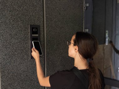 Akıllı ev kavramı. Genç kızlara yakın çekim. Elektronik kilidi açmak için cep telefonu kullan. Yüksek kalite fotoğraf