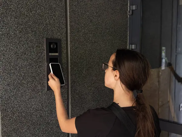 Akıllı ev kavramı. Genç kızlara yakın çekim. Elektronik kilidi açmak için cep telefonu kullan. Yüksek kalite fotoğraf