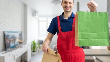 Elinde kağıt torba tutan yakışıklı bir genç..