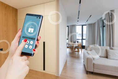 Mobil uygulamada ev sıcaklığı, güvenlik ve çevre kontrolü. Kadın elinde akıllı telefon. Arka planda oturma odası.