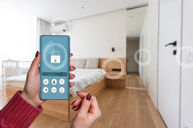 Akıllı ev, ev otomasyonu, uygulama simgeli aygıt. Kadın akıllı telefonunu akıllı güvenlik uygulaması ile evinin kapısını açmak için kullanıyor.