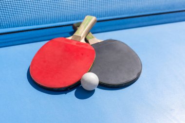 İki masa tenisi ya da masa tenisi raketi ve top mavi masada ağlı. Yüksek kalite fotoğraf