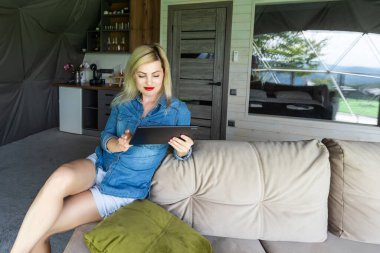 Tablet tutarak ve evde oturan genç kadın