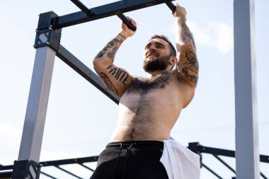 Bir adam egzersiz makineleriyle sokakta antrenman yapıyor..