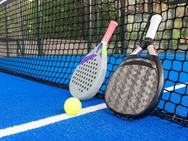 Paddle tennis: Paddel racket and ball in front of an outdoor court. High quality photo clipart