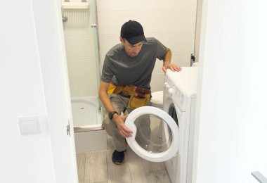 Tesisatçı beyaz arka planda çamaşır makinesini tamir ediyor. Yüksek kalite fotoğraf