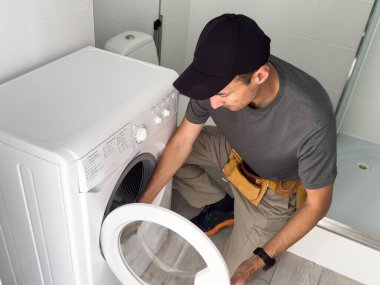 Tesisatçı beyaz arka planda çamaşır makinesini tamir ediyor. Yüksek kalite fotoğraf