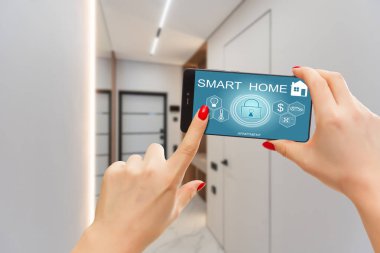 Akıllı ev otomasyon uygulaması arka planda iç mekan olan kadın eliyle akıllı telefondan tutulmuş. Yüksek kalite fotoğraf