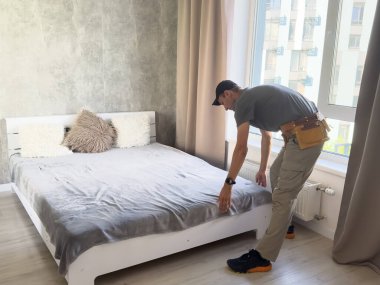 Ev ödevi. Orta yaşlı bir adam yeni yatak örtüsü örtür. Yüksek kalite fotoğraf