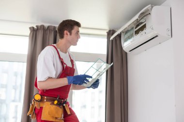 Yeni klima ünitesini bağlayan işçi..