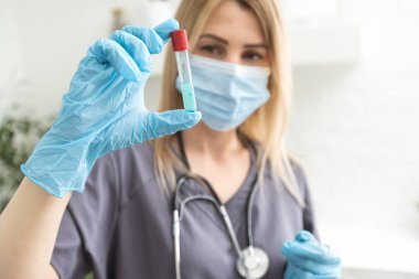 Biyolojik tehlike. Çin koronavirüsü salgını. Koruyucu maskeli bir kadın şırınga ve aşı taşıyor. Aşı gribi, koronavirüs, ebola, tüberküloz