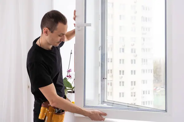 stock image Young repairman fixing window frame in room at daytime. High quality photo