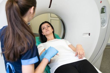 Radyolog, bilgisayarlı tomografi odasında bir kadın hasta ile birlikte.