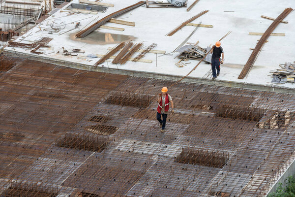 Construction workers install formwork and iron rebars or reinforcing bar for reinforced concrete partitions at the construction site of a large residential building. High quality photo