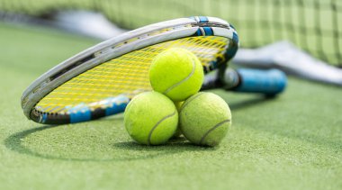 Makro tenis topu ve raket sert kortta. Arka planda bulanık ağ var. Yüksek kalite fotoğraf