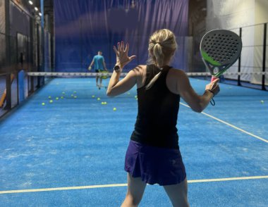  Bir kadın Padel oynuyor, açık mavi bir sahada topa vuruyor. Yüksek kalite fotoğraf