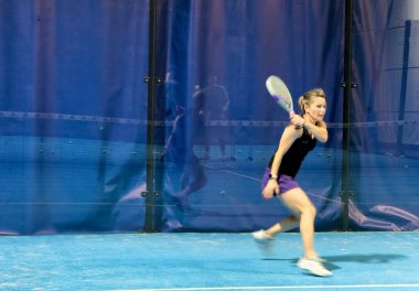  Bir kadın Padel oynuyor, açık mavi bir sahada topa vuruyor. Yüksek kalite fotoğraf