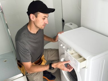 Tesisatçı beyaz arka planda çamaşır makinesini tamir ediyor. Yüksek kalite fotoğraf