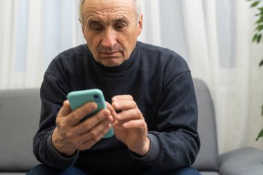 Akıllı telefon kullanan yaşlı bir adam, cep telefonunu erkeklerin elinde tutuyor. Emeklilik, SMS ve sosyal medyada çevrimiçi iletişim kavramı